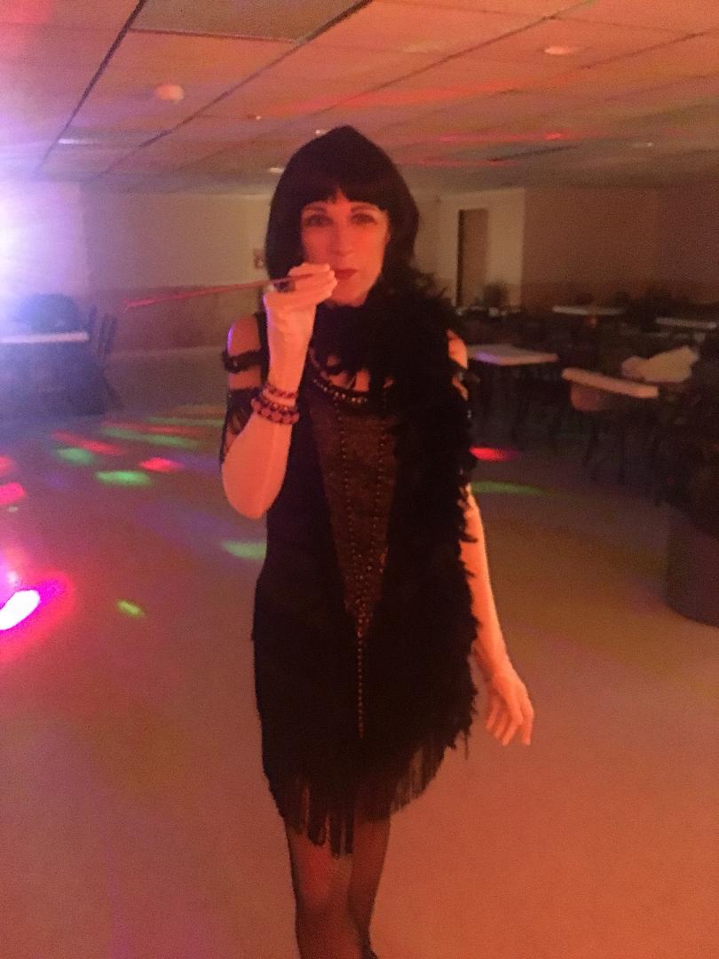 A woman in a black dress and feather boa posing in a dimly lit room with disco lights. A woman in a black dress and feather boa posing in a dimly lit room with disco lights.