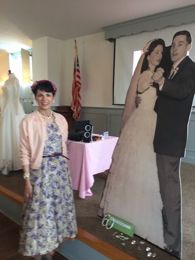 A photo of a wedding dress display with a cardboard cutout of a couple and a mannequin wearing a floral dress. A photo of a wedding dress display with a cardboard cutout of a couple and a mannequin wearing a floral dress.