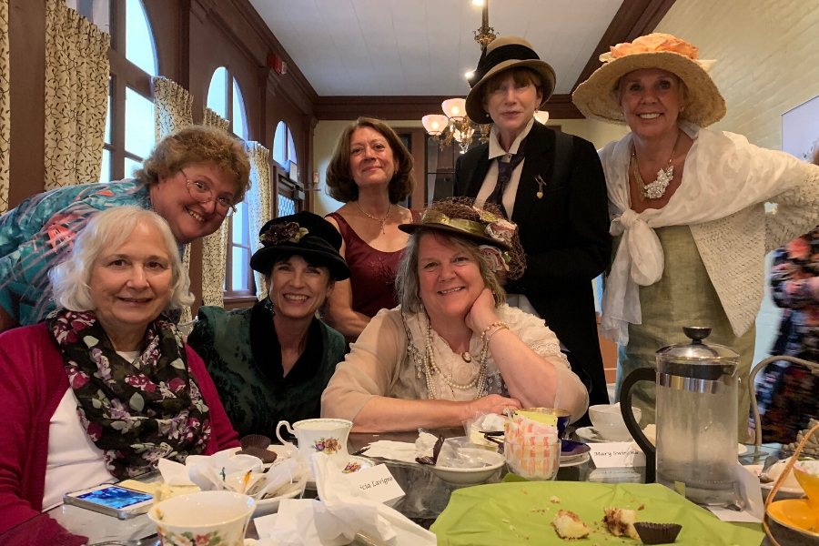 A group of women in vintage fashion costumes having a tea party in a decorated room. A group of women in vintage fashion costumes having a tea party in a decorated room.