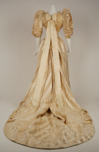 Photo of a cream-colored wedding dress with a floral pattern and a bow on a mannequin Photo of a cream-colored wedding dress with a floral pattern and a bow on a mannequin