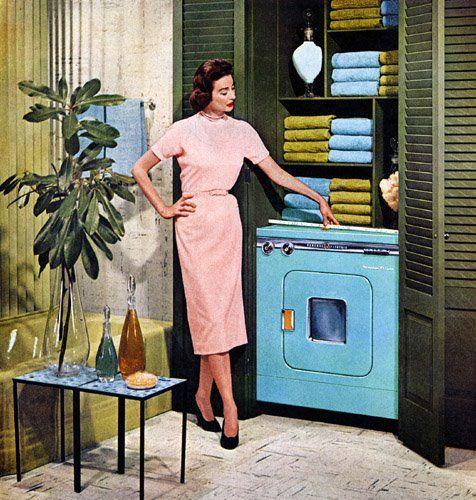 A woman in a pink dress standing next to a blue washing machine in a retro style room. A woman in a pink dress standing next to a blue washing machine in a retro style room.