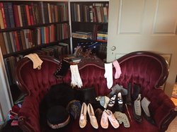 A photo of a cozy living room with a red velvet couch, various shoes, and a bookshelf.