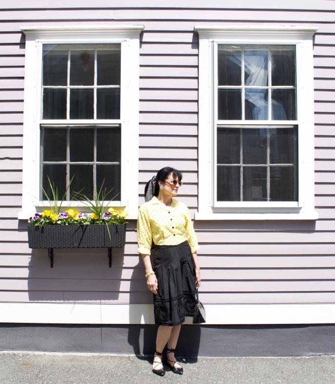 A person standing in front of a light pink house with a flower box. A person standing in front of a light pink house with a flower box.