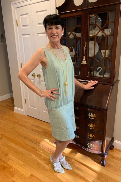 Photo of a woman in a blue dress standing in a room with wooden flooring and a cabinet Photo of a woman in a blue dress standing in a room with wooden flooring and a cabinet